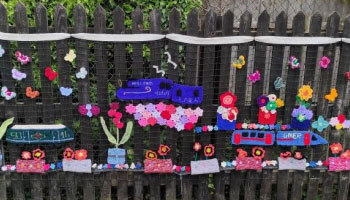 knitted trains on a fence