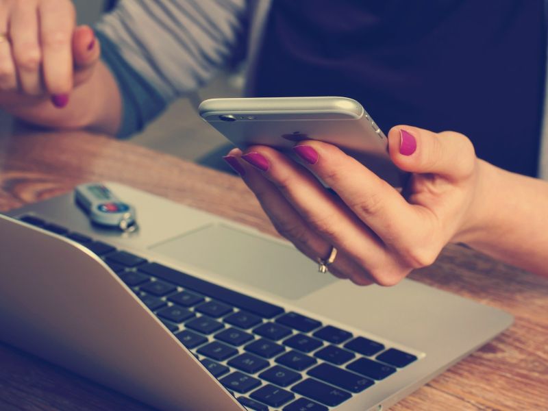 laptop with person's hand holding phone
